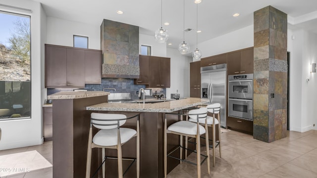 1805 E Rocky Slope Dr, Phoenix, AZ 85048 - kitchen featuring an island with sink, backsplash, appliances with stainless steel finishes, a breakfast bar area, and dark brown cabinets