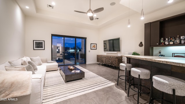 1805 E Rocky Slope Dr, Phoenix, AZ 85048 - living room with visible vents, a tray ceiling, baseboards, bar area, and ceiling fan