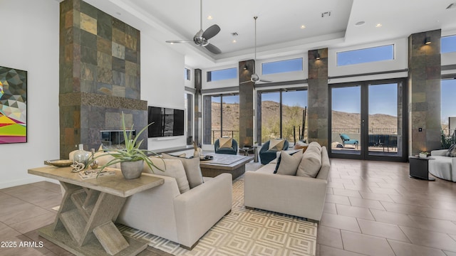 1805 E Rocky Slope Dr, Phoenix, AZ 85048 - tiled living room featuring visible vents, a ceiling fan, a tray ceiling, a fireplace, and a towering ceiling