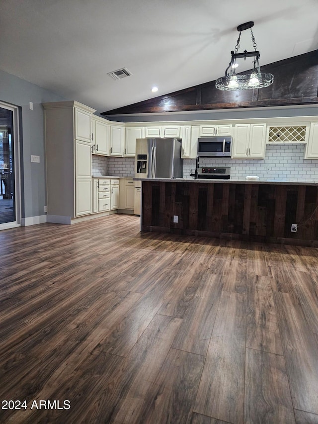 kitchen with vaulted ceiling, decorative backsplash, appliances with stainless steel finishes, decorative light fixtures, and wood-type flooring