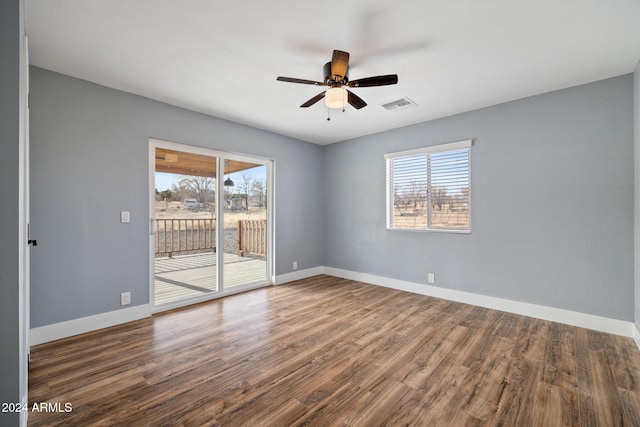 empty room with ceiling fan, a healthy amount of sunlight, and dark wood-type flooring