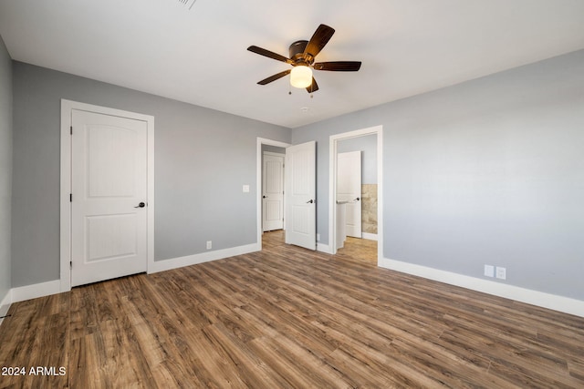 unfurnished bedroom with ceiling fan, ensuite bathroom, and wood-type flooring