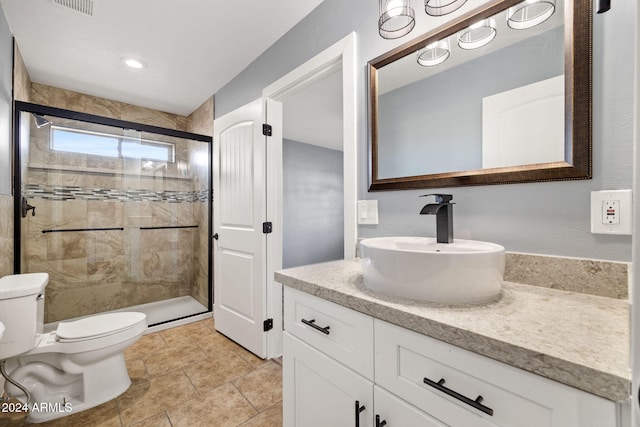 bathroom featuring tile patterned floors, vanity, toilet, and a shower with shower door