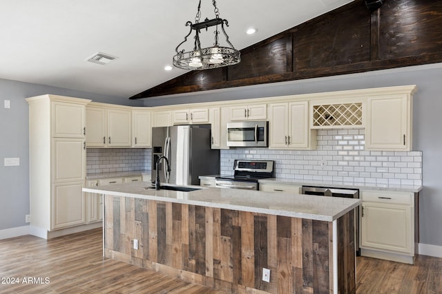 kitchen featuring sink, pendant lighting, stainless steel appliances, and cream cabinetry