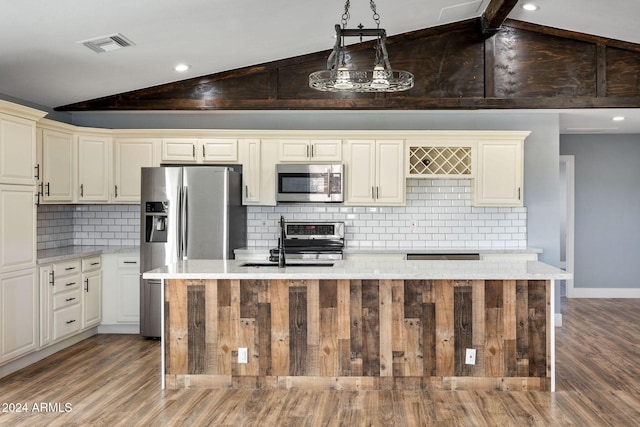 kitchen with hardwood / wood-style flooring, vaulted ceiling with beams, stainless steel appliances, and cream cabinets