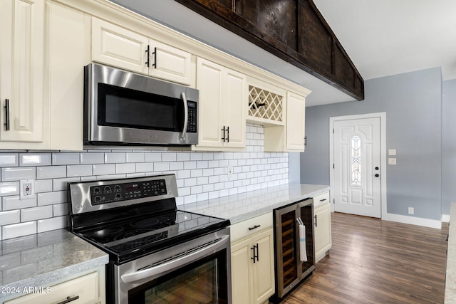 kitchen with cream cabinetry, dark hardwood / wood-style flooring, light stone counters, stainless steel appliances, and beverage cooler