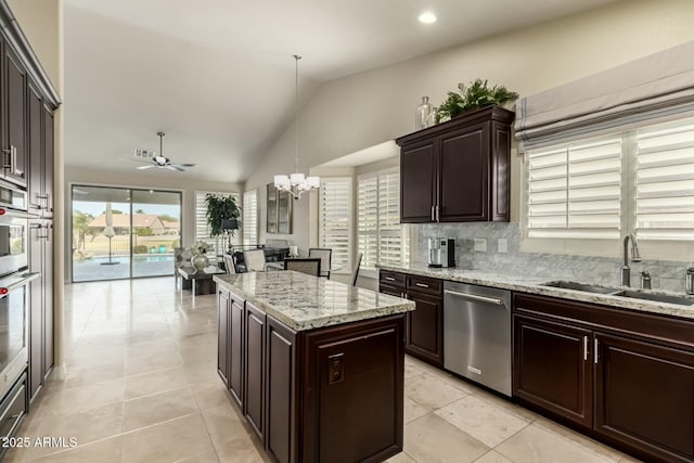 kitchen featuring a center island, decorative light fixtures, lofted ceiling, appliances with stainless steel finishes, and sink