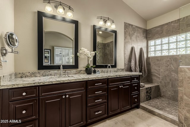 bathroom featuring vaulted ceiling, tiled shower, and vanity