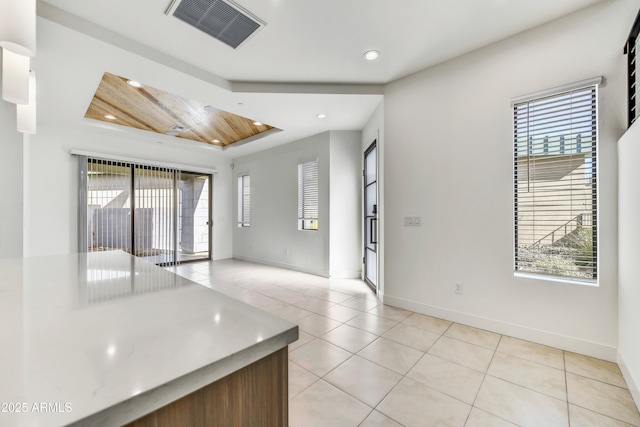 unfurnished room with wooden ceiling, light tile patterned flooring, and a wealth of natural light