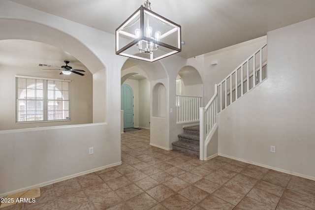 spare room featuring ceiling fan with notable chandelier