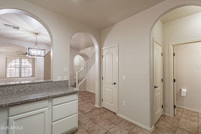 kitchen with dark stone counters, decorative light fixtures, and white cabinets