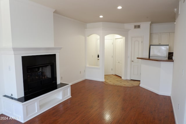 unfurnished living room with dark hardwood / wood-style flooring and ornamental molding