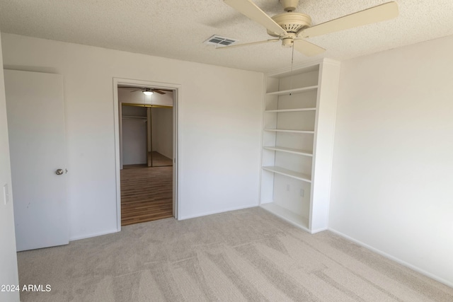 unfurnished bedroom with ceiling fan, a closet, light colored carpet, and a textured ceiling