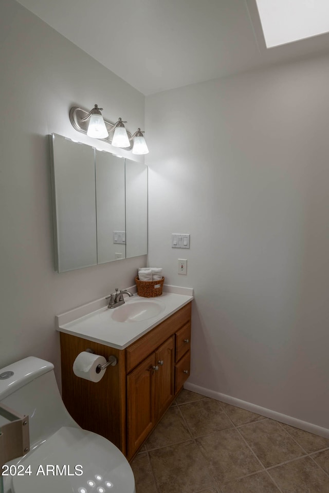 bathroom with tile patterned floors, vanity, a skylight, and toilet