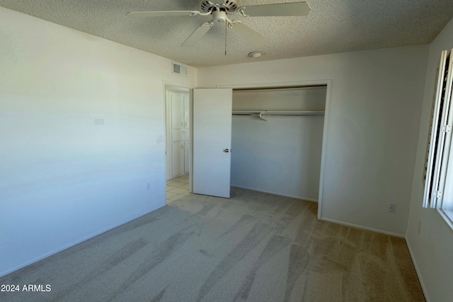 unfurnished bedroom featuring a textured ceiling, ceiling fan, light carpet, and a closet