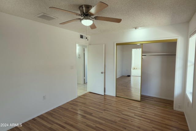 unfurnished bedroom with hardwood / wood-style floors, a textured ceiling, a closet, and ceiling fan