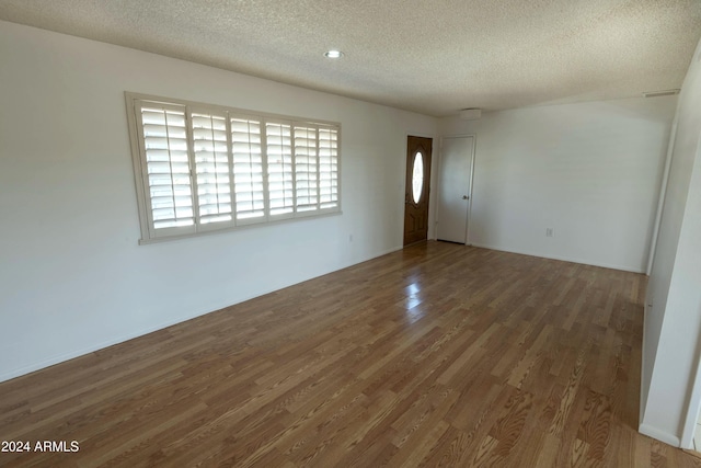 unfurnished room with dark hardwood / wood-style flooring and a textured ceiling