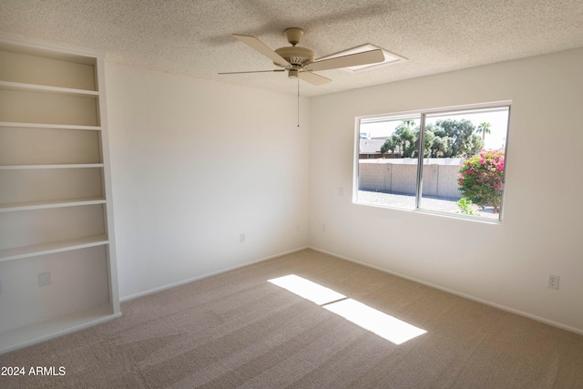 carpeted spare room featuring ceiling fan and a textured ceiling