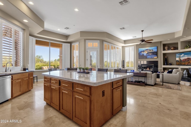 kitchen with sink, light stone counters, ceiling fan, a center island, and dishwasher