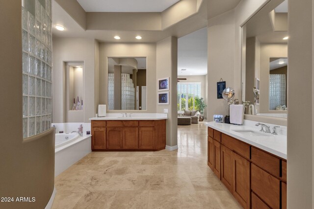 bathroom with ceiling fan, a tub to relax in, and vanity