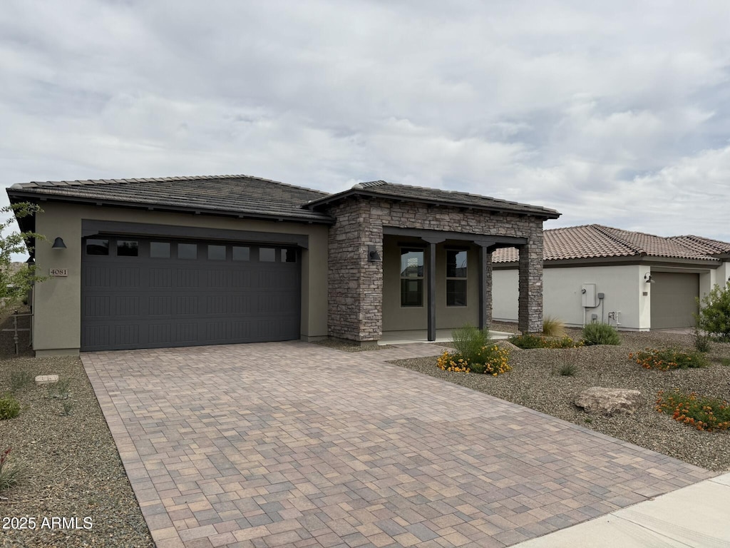 4081 Fence Post Way, Wickenburg, AZ 85390 - view of front of home featuring stucco siding, decorative driveway, a garage, and covered porch