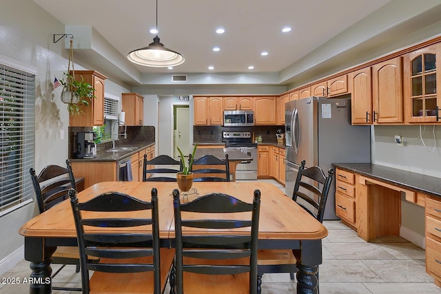 kitchen featuring a sink, stainless steel appliances, baseboards, decorative backsplash, and glass insert cabinets