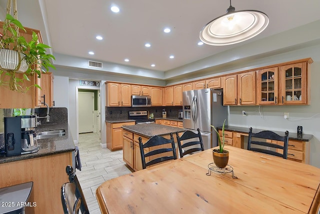 kitchen featuring stainless steel appliances, decorative backsplash, a kitchen island, visible vents, and glass insert cabinets
