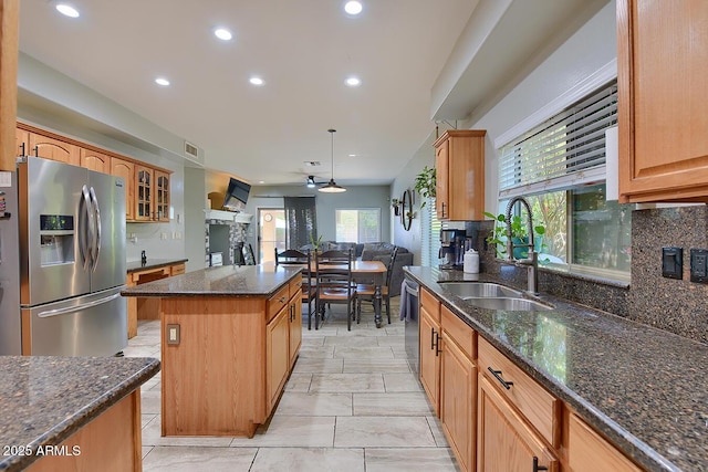 kitchen with a center island, a sink, decorative backsplash, and appliances with stainless steel finishes