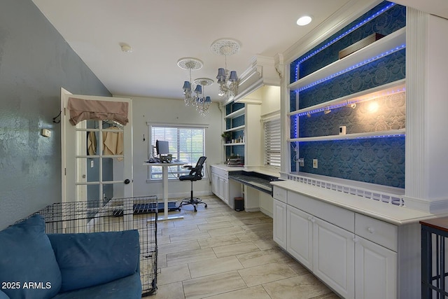 kitchen with open shelves, light countertops, built in study area, an inviting chandelier, and white cabinetry