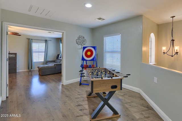 recreation room with arched walkways, baseboards, visible vents, and wood finished floors