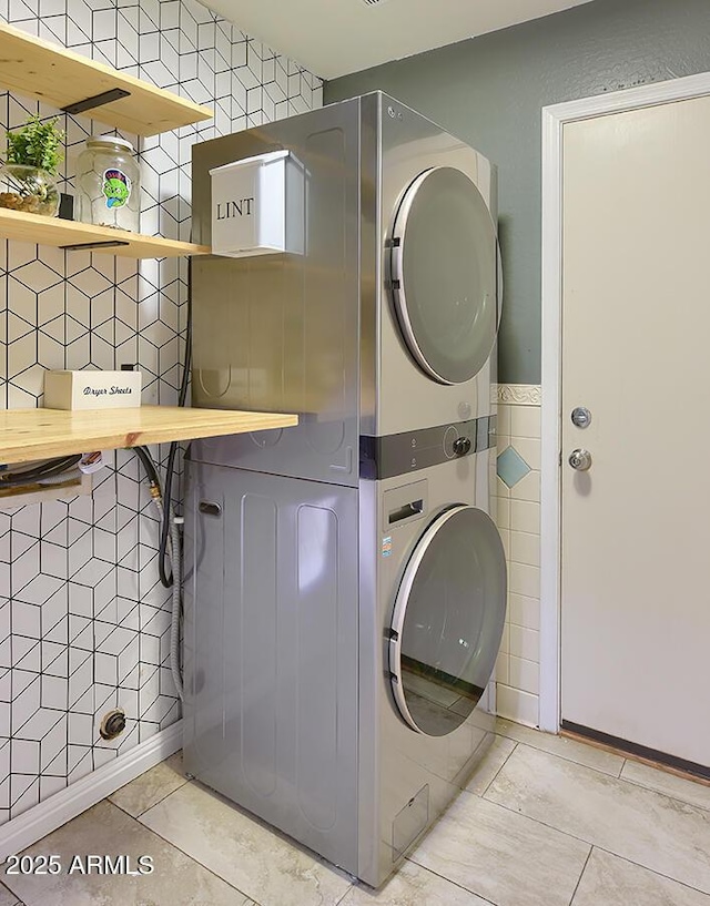 washroom featuring tile walls, tile patterned floors, laundry area, and stacked washer / drying machine
