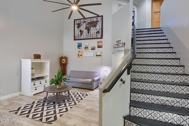 staircase featuring a ceiling fan and baseboards