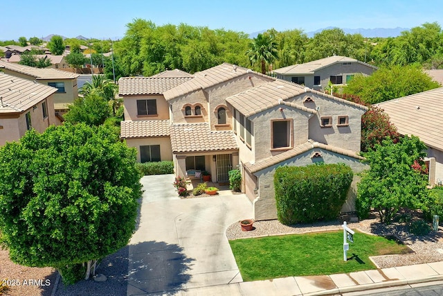 mediterranean / spanish house featuring a residential view, a tiled roof, and stucco siding
