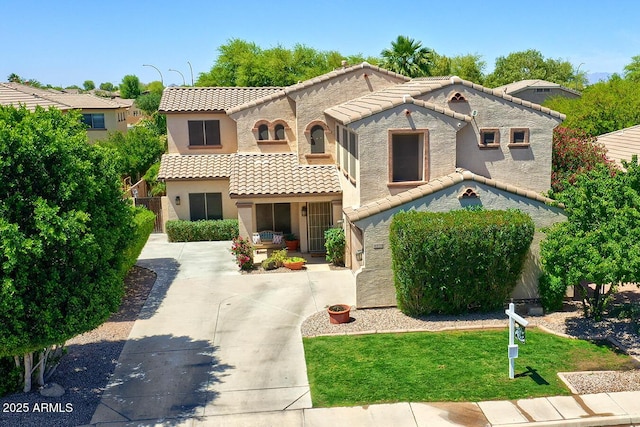 mediterranean / spanish house with fence, a front lawn, a tile roof, and stucco siding