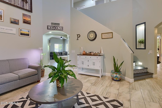 living area featuring arched walkways, a high ceiling, visible vents, and baseboards