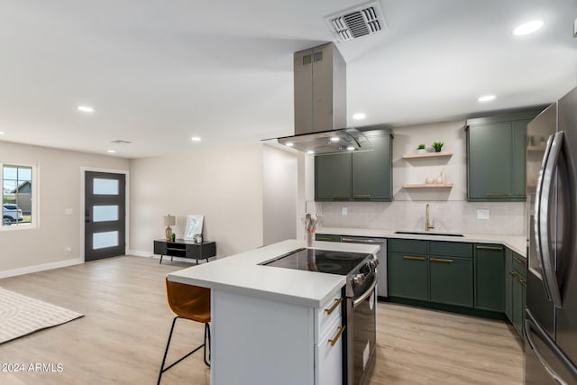 kitchen with island range hood, sink, appliances with stainless steel finishes, and light hardwood / wood-style flooring