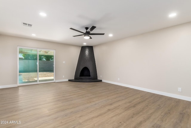 unfurnished living room with light hardwood / wood-style flooring, a large fireplace, and ceiling fan