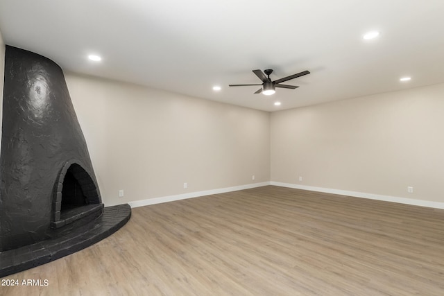 unfurnished living room featuring a large fireplace, light wood-type flooring, and ceiling fan