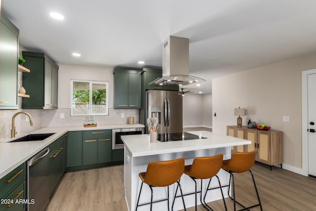 kitchen featuring sink, green cabinetry, a kitchen island, island range hood, and stainless steel appliances