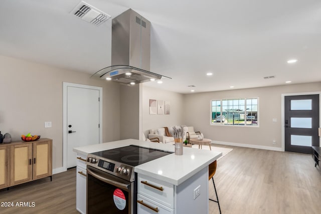 kitchen with a kitchen island, hardwood / wood-style flooring, range hood, electric range, and white cabinets