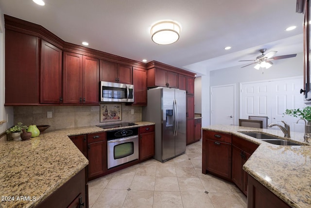 kitchen featuring light stone countertops, sink, ceiling fan, stainless steel appliances, and backsplash