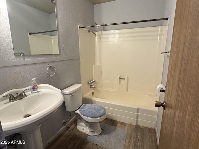 full bathroom with shower / bathtub combination, a textured wall, wood finished floors, and toilet