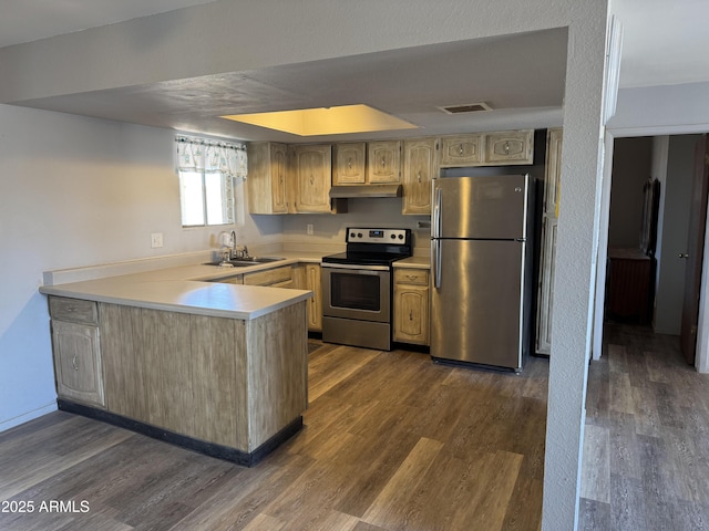 kitchen with dark wood-type flooring, a peninsula, stainless steel appliances, under cabinet range hood, and a sink