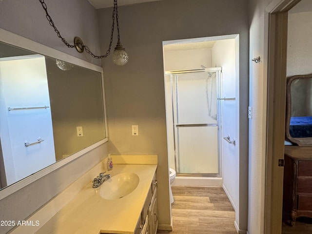 full bath featuring toilet, wood finished floors, a shower stall, and vanity