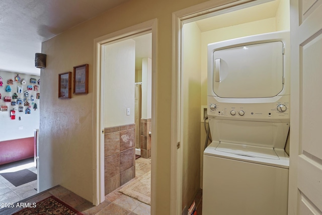 583 Reata Pass, Happy Jack, AZ 86024 - laundry area featuring stacked washer / dryer, light tile patterned floors, tile walls, and laundry area