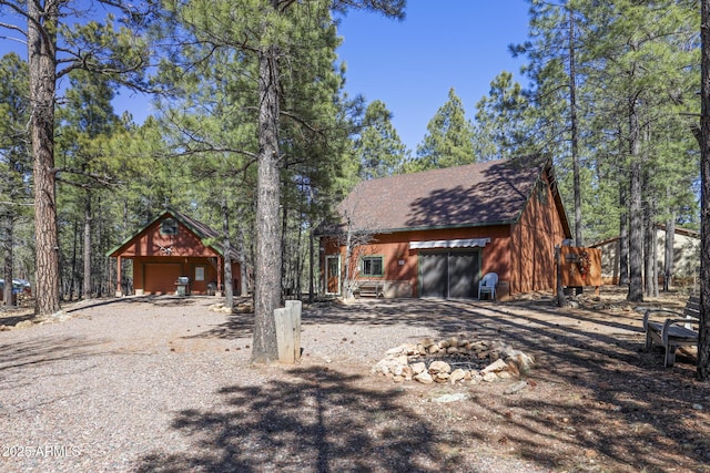 583 Reata Pass, Happy Jack, AZ 86024 - view of front of property with gravel driveway, an outdoor structure, a garage, and roof with shingles