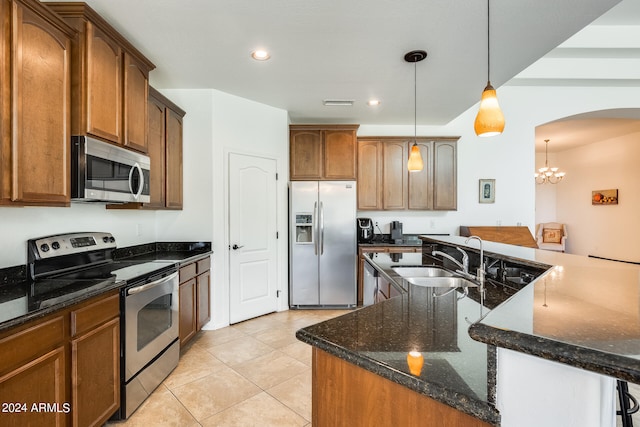 kitchen with decorative light fixtures, stainless steel appliances, a chandelier, sink, and dark stone counters