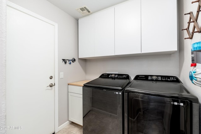 laundry area featuring cabinets, washing machine and dryer, and light tile patterned floors