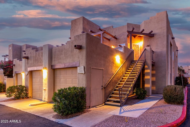 view of front of property with stairs, a garage, and stucco siding