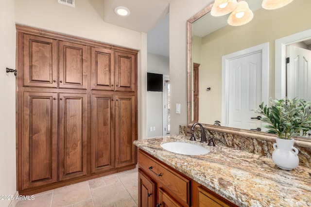 bathroom with visible vents, vanity, and stone tile floors